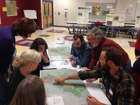 Group of adults sitting around a table looking at map of trail system.