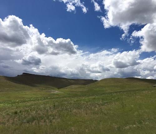 Grassy hills meeting cloudy skies in the 80 acre land purchase in the foothills. 